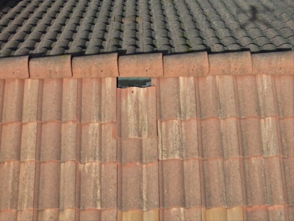 This picture shows a loose tile that has slipped down exposing the felt underlayment to the sun. The felt is almost worn through.